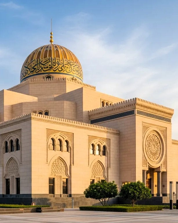 Sharjah Museum of Islamic civilization, featuring a large golden dome with Arabic calligraphy and beige stone architecture under a blue sky.